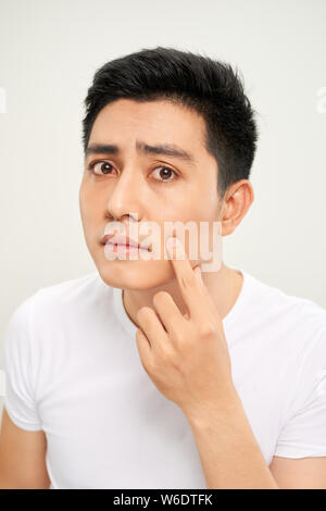 Chiudere la foto del giovane uomo cercando acnes sul suo volto Foto Stock