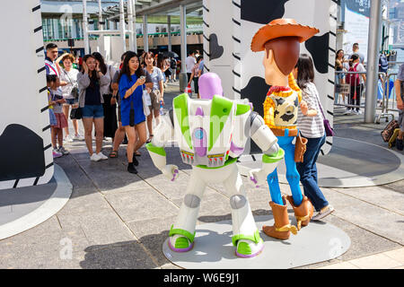 Una donna possiede accanto alle repliche dello sceriffo Woody e Buzz Lightyear durante il carnevale.Toy Story 4 è celebrato con un carnevale a tema di diversi giochi e sfide al Porto di Hong Kong City. Foto Stock