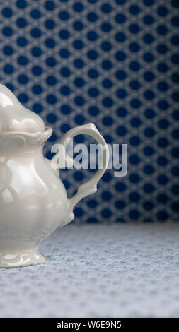 Zucchero bianco ciotola su una bianca tovaglia di pizzo. Blu non focalizzato sullo sfondo geometrico. Foto Stock