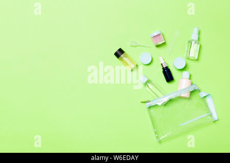 Un gruppo di piccoli flaconi per viaggiare su sfondo verde. Copia dello spazio per le vostre idee. Appartamento stabilire la composizione dei prodotti cosmetici. Vista superiore della crema con Foto Stock