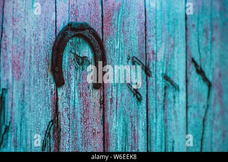 Ferro di cavallo di metallo appeso su blu porta di legno, boho stile retrò Foto Stock