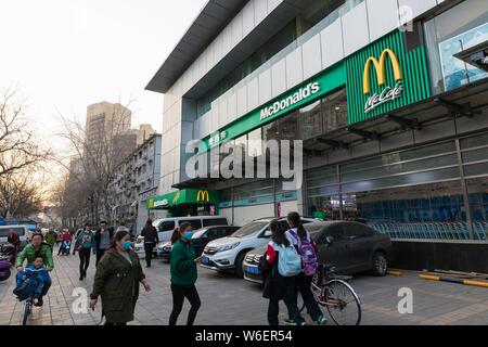 I pedoni a piedi passato un verde- e Pechino Guoan FC a tema per un fast food ristorante di McDonald in Pechino, 29 marzo 2018. McDonald's ha decora Foto Stock