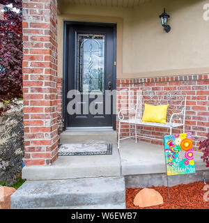 Cornice quadrata porticato con panchina di una casa con il vetro della porta vetrata e concrete e un muro di mattoni Foto Stock