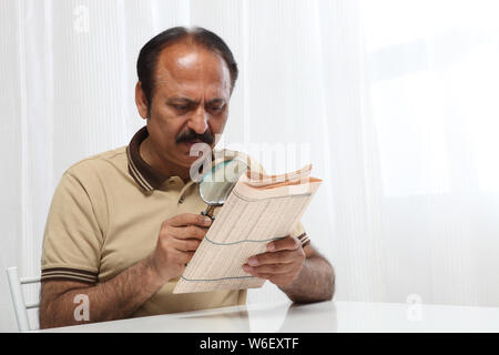 Vecchio giornale di lettura con lente di ingrandimento Foto Stock