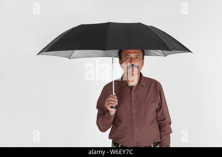 Uomo sorridente sotto un ombrello Foto Stock
