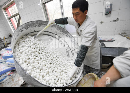 Un lavoratore cinese vorticosamente un contenitore per avvolgere le imbottiture con sticky farina di riso per rendere il riso glutinoso sfere, noto anche come Yuanxiao o Yuan Xiao, a Foto Stock