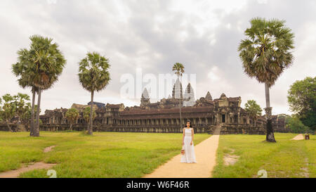 Emancipated asiatica donna solista traveler ad esplorare il tempio di Angkor Wat, Siem Reap, Cambogia in abito bianco Foto Stock