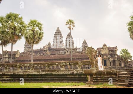 Emancipated asiatica donna solista traveler ad esplorare il tempio di Angkor Wat, Siem Reap, Cambogia in abito bianco Foto Stock