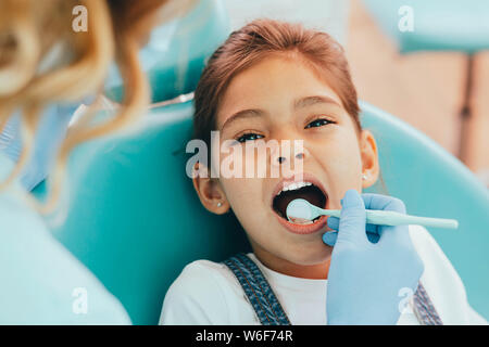 Razza mista ragazza ottenendo il suo denti esaminati con specchio dentale Foto Stock