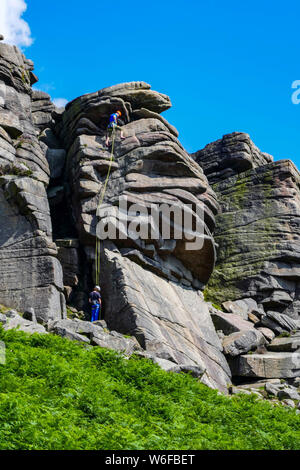 Arrampicatori sul bordo Stanage, Gritstone, Peak District National Park, England, Regno Unito Foto Stock