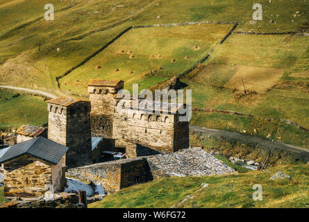 Svan tradizionali torri e case machub con lastricato in Ushguli comune contro i grandi colline di erba, Svaneti superiore, Georgia Foto Stock