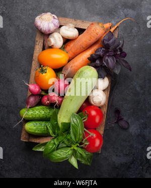 Un assortimento di materie gli ortaggi biologici, le erbe aromatiche e le spezie. Fresco giardino cibo vegetariano. Vista dall'alto sul tavolo di pietra Foto Stock