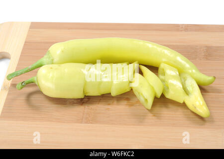 Affettato e tutta la banana peppers sul tagliere di legno Foto Stock