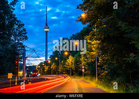 Germania, Stuttgart City torre televisiva, fernsehturm nel Magico crepuscolo nascente atmosfera dopo il tramonto dietro la strada con il traffico nella foresta Foto Stock