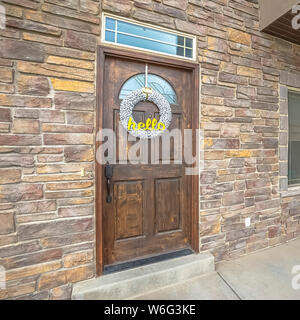 Piazza la facciata della casa con portico di pietra della parete di mattoni marroni e porta sopraluce Foto Stock