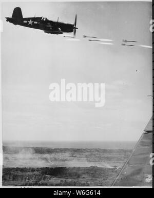 Corsair fighter perde il suo carico di proiettili a razzo su una corsa contro una roccaforte Jap su Okinawa. Nella parte inferiore di sfondo è il fumo della battaglia come le unità marine si muovano per seguire con un punzone di domenica, ca. 06/1945 Foto Stock