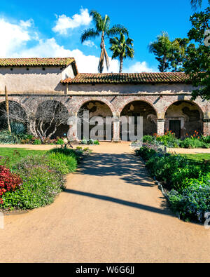 Immagine delle arcate in mattoni e il corridoio preso dal giardino presso la missione di San Juan Capistrano. Foto Stock