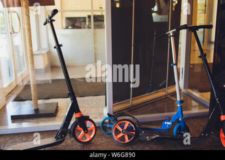 Biciclette e scooter elettrici parcheggiato sulla strada della citta'. Self-service di trasporto strada servizio di noleggio. Noleggio veicolo urbano con applicazione dello smartphone Foto Stock