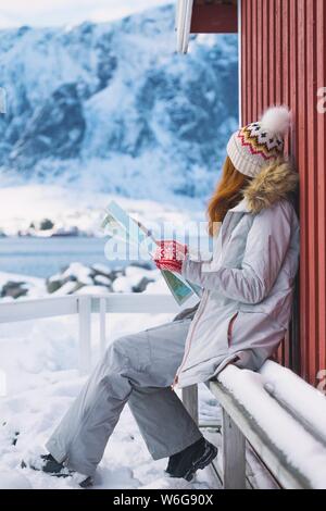 Ragazza turistica si siede vicino rorbu con una mappa a isole Lofoten. Norvegia Foto Stock