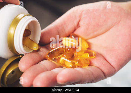 Vecchia donna versando olio di pesce capsule dalla bottiglia, close up Foto Stock