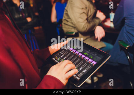 Evento di controllo di sintonizzazione audio dal tablet sullo sfondo di un karaoke bar. Foto Stock