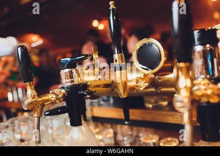 I rubinetti di birra in un pub. Nessuno. Messa a fuoco selettiva. Concetto di alcol. In stile vintage. La birra artigianale. Tavolo bar. Maschi in acciaio. Shiny rubinetti. Foto Stock