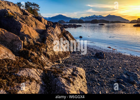 Tramonto invernale su una spiaggia rocciosa che si affaccia su Crescent Bay; Sitka, Alaska, Stati Uniti d'America Foto Stock