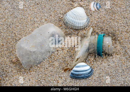 Vecchio parzialmente ripartiti in bottiglia di plastica e non di rifiuti biodegradabili si è incagliata sulla spiaggia di sabbia lungo la costa del Mare del Nord Foto Stock