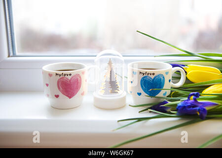 Bellissimi fiori-tulipani e iris giacciono sul davanzale con due tazze di caffè. Foto Stock