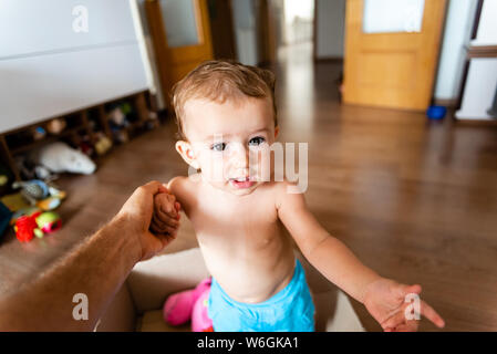 Il padre tiene la sua bimba la mano per aiutare il suo fuori da una scatola di cartone in cui ella è la riproduzione. Foto Stock