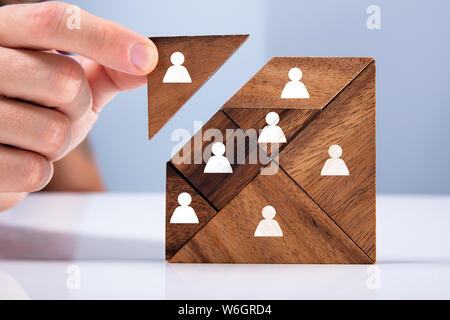 Close-up di mano d'uomo in possesso di un pezzo mancante in un quadrato Tangram Puzzle Foto Stock