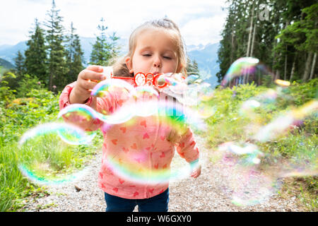 Ragazza a soffiare bolle in una giornata di sole nel parco Foto Stock