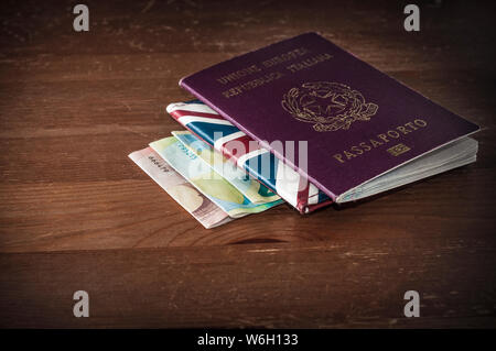 Concetto di viaggio immagine: un passaporto italiano su una unione jack portafoglio e alcune banconote in euro su un tavolo di legno Foto Stock