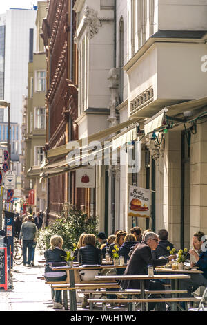 Berlino, Germania - 26 settembre 2018: prospettiva verticale dell'architettura di alcuni edifici del marciapiede di una strada trafficata con gente seduta Foto Stock