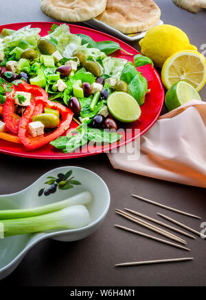 Un colpo verticale di un appetitoso tradizionale insalata con limone e lime per la ravvivatura e pane pita. Foto Stock