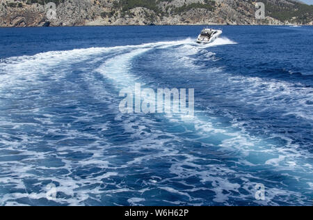 Imbarcazione a motore accelerando rendendo le onde spumeggianti in blu mediterraneo acqua su una soleggiata giornata estiva a Mallorca, Spagna. Foto Stock