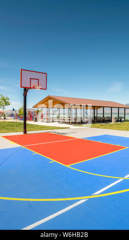 All'aperto verticale pallacanestro con un padiglione di picnic e parco giochi in background Foto Stock