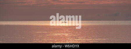 Barca dei pescatori contro silhouette orange sunrise sul Lago Malawi, il sole glitter sul lago, sud-est-africa Foto Stock