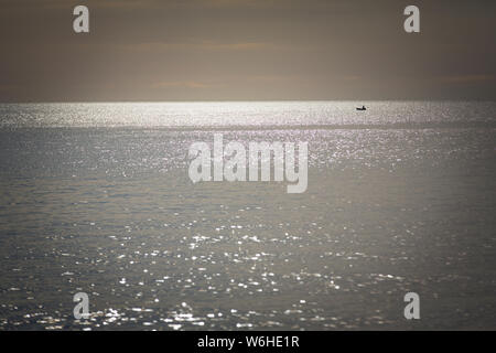 Barca dei pescatori silhouette contro Alba sul lago Malawi, il sole glitter sul lago, sud-est-africa Foto Stock