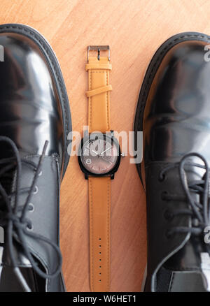 Meccanico classico orologio da polso stabilire tra la coppia di uomo nero scarpe formali. vista superiore Foto Stock