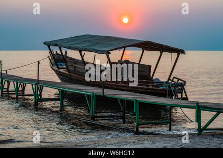 Tramonto dietro imbarcazione attraccata alla darsena di mbali Mbali Mahale Lodge (Kungue Beach Lodge) sul Lago Tanganica; Tanzania Foto Stock