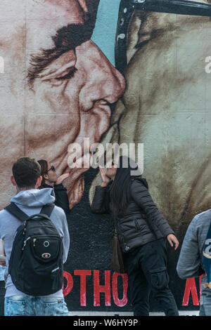 Berlino, Germania - 26 Settembre 2018: turisti fotografare vicino al 'Il Bacio' pittura presso il Muro di Berlino, un iconico immagine del leader sovietico Foto Stock