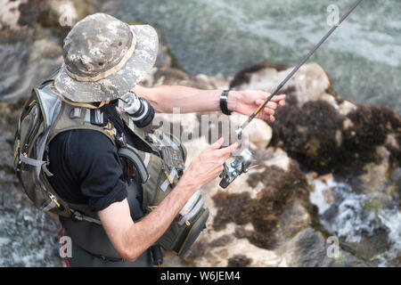 L'uomo la pesca nel fiume. fisher in acqua. fisherman Visualizza tecnica di pesca l'uso. Asta. hobby e attività sportiva . Foto Stock