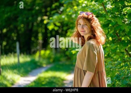 I giovani i capelli rossi donna in una foresta, su un percorso, Alta Baviera, Germania Foto Stock