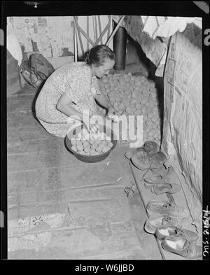 La sig.ra Charlie Davis ottenere patate da conservazione sotto il tavolo in cucina di due loro casa in camera. Il Davises sollevare qualche orto roba per uso domestico. Coleman Fuel Company, Uccello Rosso miniera, campo, Bell County, Kentucky Foto Stock