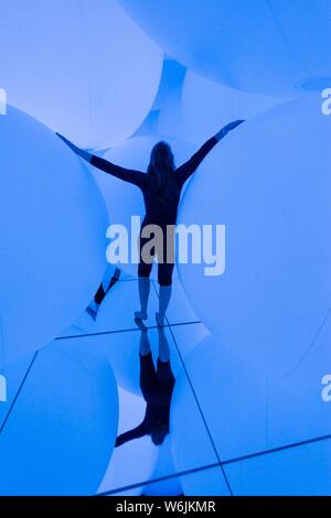 Giovane donna, grande illuminato sfere, installazione LED nel Digital Art Museum, TeamLab pianeti, Koto City, Tokyo, Giappone Foto Stock