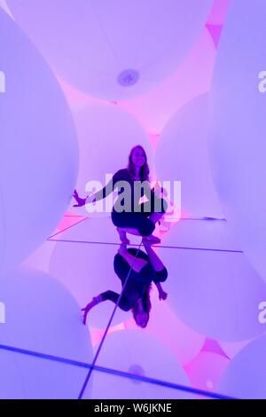 Giovane donna, grande illuminato sfere, installazione LED nel Digital Art Museum, TeamLab pianeti, Koto City, Tokyo, Giappone Foto Stock