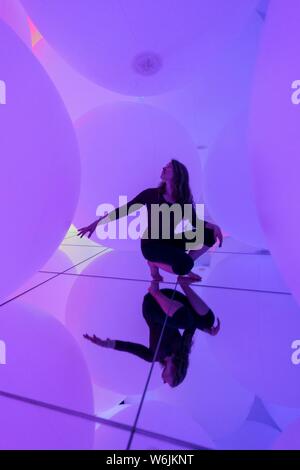 Giovane donna, grande illuminato sfere, installazione LED nel Digital Art Museum, TeamLab pianeti, Koto City, Tokyo, Giappone Foto Stock