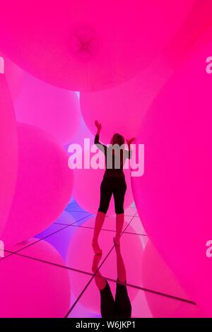 Giovane donna, grande illuminato sfere, installazione LED nel Digital Art Museum, TeamLab pianeti, Koto City, Tokyo, Giappone Foto Stock