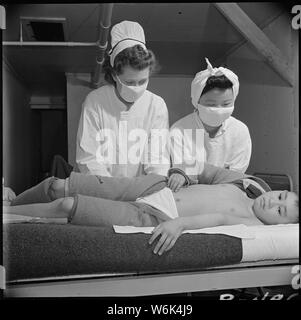 Poston, Arizona. Registered Nurse, la sig.ra Edythe Sasser, è assisited da Yoshiko Konatsu, infermiere di aiuto . . .; Portata e contenuto: tutta la didascalia per questa fotografia si legge: Poston, Arizona. Registered Nurse, la sig.ra Edythe Sasser, è assisited da Yoshiko Konatsu, infermiere, aiuto e Tomiko Kitasaki, infermiere, aiuti per il trattamento di paralisi infantile. Tutti i pazienti affetti da questa malattia dread sono trattati mediante il metodo di Kenny. Hot Pack sono applicate alle arti colpiti e questo è seguita da muscolare e nervoso di rieducazione. Foto Stock